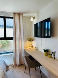 a bedroom with a desk and a bed and a window at 6 Suites Signature in Saint-Jacques-de-la-Lande