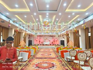 a man standing in a hall with chairs and a rug at Hotel Shaktideep in Pushkar