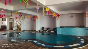 a swimming pool in a room with chairs and kites at Hotel Shaktideep in Pushkar