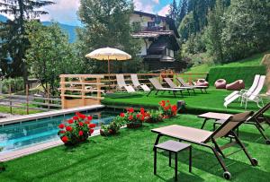 a yard with chairs and a swimming pool with flowers at Hotel Dahu in Madonna di Campiglio
