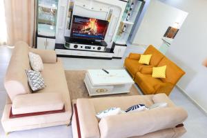 a living room with two couches and a tv at Zeus Boutique Apartment in Kigali +8 photos