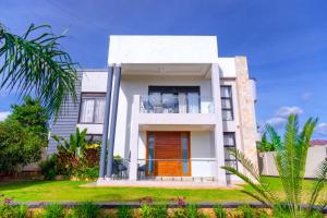 a white house with a balcony on a lawn at Zeus Boutique Apartment in Kigali