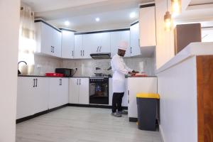 a chef standing in a kitchen preparing food at Zeus Boutique Apartment in Kigali