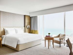 a bedroom with a bed and a desk and a chair at Pullman Doha West Bay in Doha