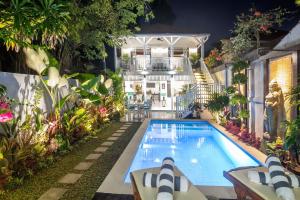 a swimming pool in a garden with a house at Selasih Beach House in Seminyak