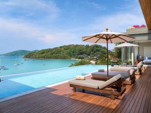 a swimming pool with lounge chairs and an umbrella at V Villas Phuket - MGallery Collection in Panwa Beach