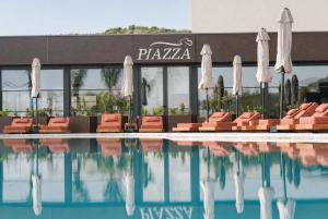 a pool with chairs and umbrellas in front of a hotel at Chaonian Hotel in Dhërmi