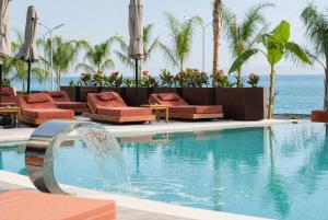 a swimming pool with a fountain in front of the ocean at Chaonian Hotel in Dhërmi