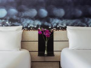 a vase of purple flowers sitting between two beds at Novotel Mexico City Toreo in Mexico City