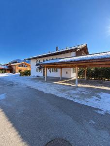 a building with snow on the ground next to a road at Alpenwohnung Neuner in Wallgau