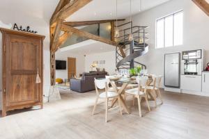 a dining room and living room with a table and chairs at Loft côté jardin in Suippes