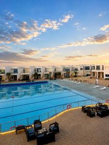 a large swimming pool with chairs and buildings in the background at اويسس Oasis in Jeddah