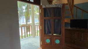 a door to a room with a television and a balcony at Thambapanni Villa in Unawatuna