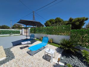 a patio with two blue chairs and an umbrella at Greek Memories in Artemida