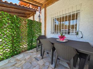 a table and chairs on a patio with a green hedge at Greek Memories in Artemida
