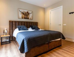 a bedroom with a bed with a cow picture on the wall at Veluwe Villa with Indoor Pool & Wellness | 12 persons in Wekerom +29 photos