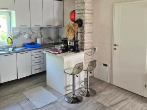 a kitchen with white cabinets and a counter with stools at Vila Dolina Izvora in Sarajevo