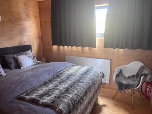 a bedroom with a bed and a chair and a window at Ferienhaus an der Wasserkuppe in Poppenhausen