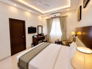 a bedroom with a bed and a desk and a television at Hotel Sai Jashan Shirdi - Where blessings & comfort meet in Shirdi