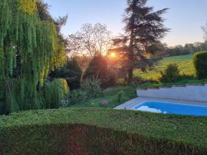 a swimming pool in a garden with the sunset in the background at L'Eclat de menthe in Augerolles