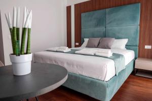 a bedroom with a bed with a blue headboard and a table at Tirone Luxury Rooms in Cirò Marina