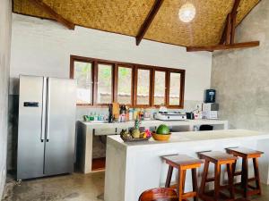 a kitchen with a refrigerator and some bar stools at The Villa Indah Areguling in Kuta Lombok +41 photos