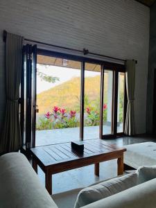a living room with a table and a large window at The Villa Indah Areguling in Kuta Lombok