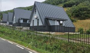 a house with a black roof and a fence at E&T-Cabin A frame in Sibiu