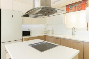 a kitchen with white cabinets and a stainless steel hood at Royal Luxury Villa by AKTIS VILLAS in Kriopigi