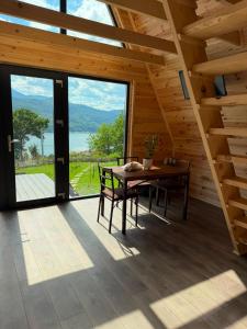 a dining room with a table and chairs and a large window at Vis de Munte Chalet in Buhalniţa