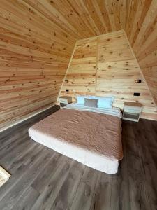 a bedroom with a bed in a wooden room at Vis de Munte Chalet in Buhalniţa
