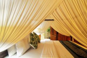 a bedroom with a canopy bed with white curtains at The Cottage By Selasih in Seminyak +22 photos