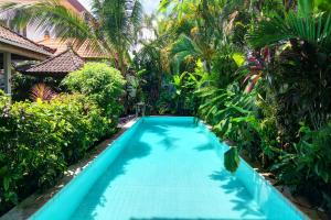 a swimming pool in front of a house with palm trees at The Cottage By Selasih in Seminyak