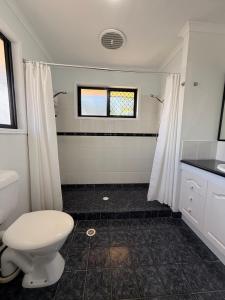 a bathroom with a white toilet and a shower at Beachside Studio Apartment in Bargara