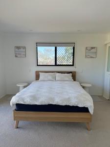 a bedroom with a large bed with two tables at Beachside Studio Apartment in Bargara