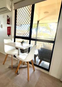 a table and chairs in a room with a large window at Beachside Studio Apartment in Bargara +19 photos
