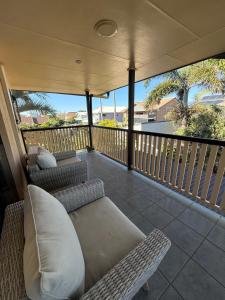 a porch with couches and chairs on a balcony at Beachside Studio Apartment in Bargara