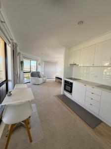 a kitchen with white cabinets and a table and chairs at Beachside Studio Apartment in Bargara
