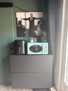 a microwave on a dresser with a picture of a man at Independent charming studio in Gibel
