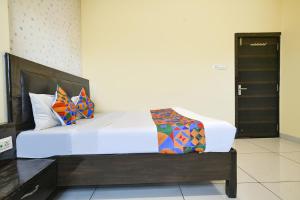 a bedroom with a large white bed with colorful pillows at FabHotel Shree I in Indore