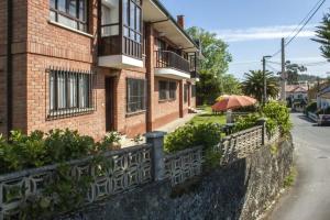 a brick building with a fence and an umbrella at La Xastra in Celorio