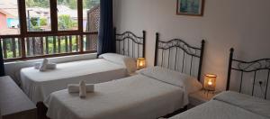 a room with two beds and two lamps and windows at La Xastra in Celorio