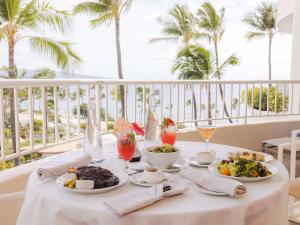 a table with food and drinks on a balcony with palm trees at Fairmont Kea Lani, Maui in Wailea