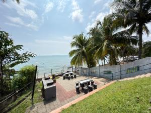 a view of the ocean with benches and palm trees at NEWLY REnOVATED Comfy Beachfront View at Seri Bulan Port Díckson in Port Dickson