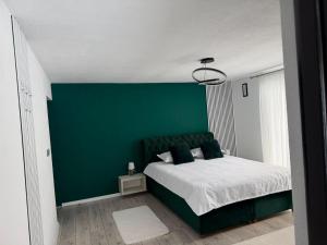 a bedroom with a green accent wall and a bed at Casa Runc in Şarul Dornei