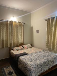 a small bedroom with a bed and curtains at Mandira Homes in Mysore