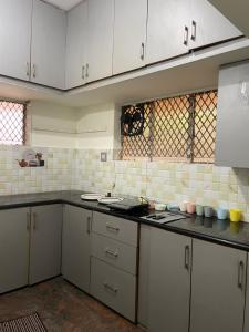 a kitchen with white cabinets and a black counter top at Mandira Homes in Mysore