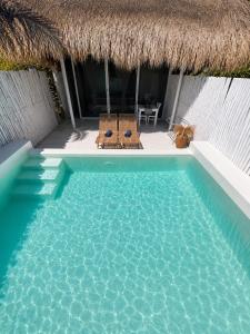 a swimming pool with two chairs and a thatch hut at Villa Samalas Boutique Resort & Private Pool Villas in Gili Meno