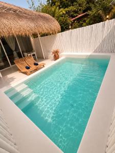 a pool with two chairs and a thatch roof at Villa Samalas Boutique Resort & Private Pool Villas in Gili Meno