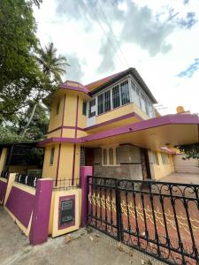 a yellow and pink house with a black fence at Mandira Homes in Mysore